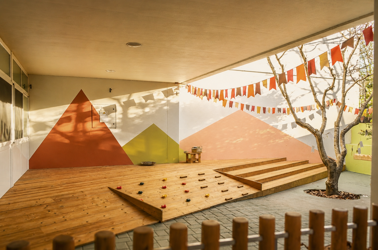 Espacio educativo exterior con estructuras de juego, madera y vegetación para el aprendizaje infantil