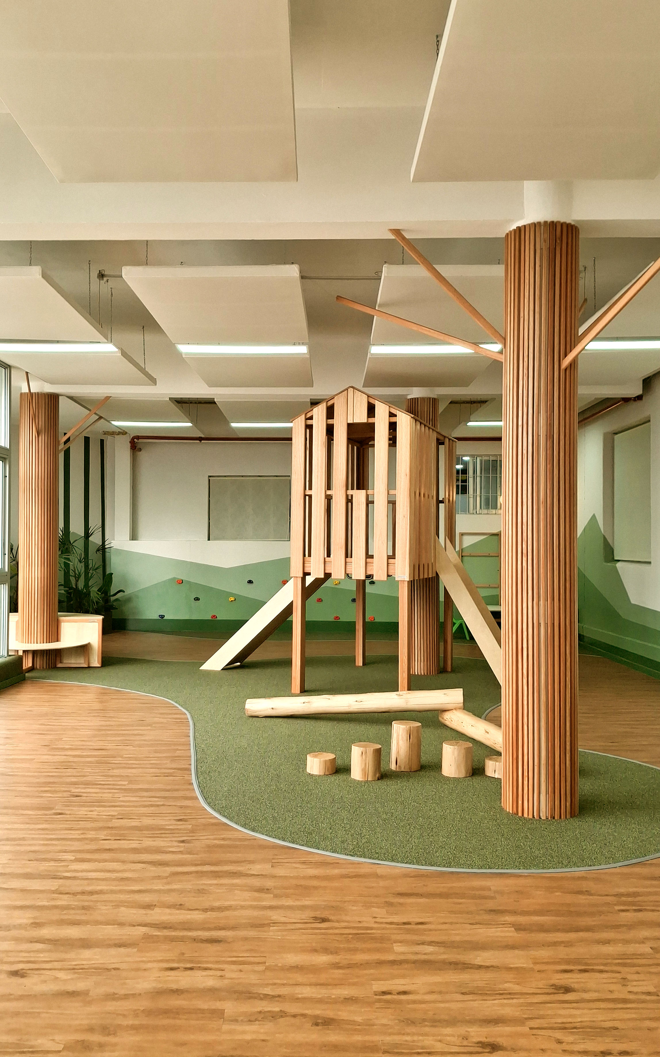 Espacio educativo exterior con estructuras de juego, madera y vegetación para el aprendizaje infantil